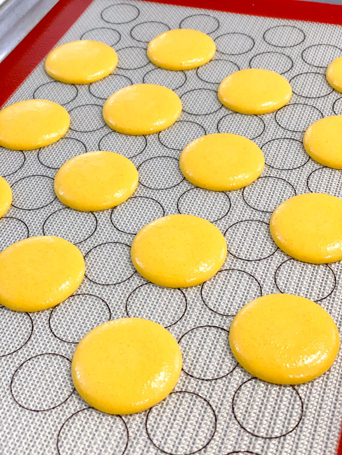 unbaked yellow macarons on baking mat