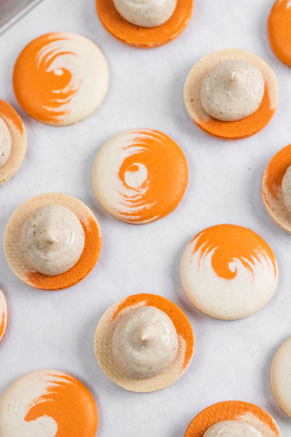 orange and white swirled pumpkin cheesecake macaron shells with cheesecake filling