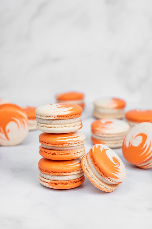 small tower of orange and white swirled pumpkin cheesecake macarons