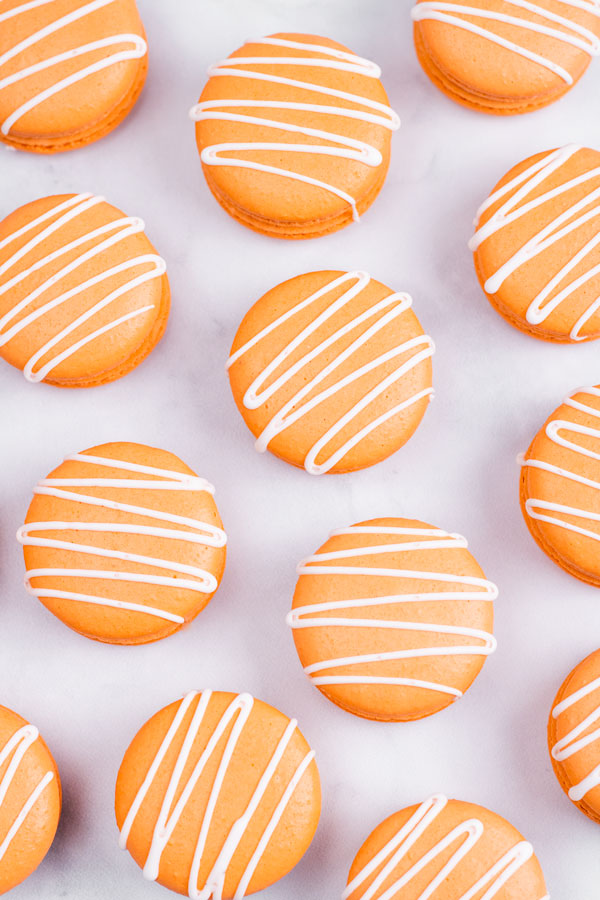 Orange pumpkin spice macarons with white drizzle