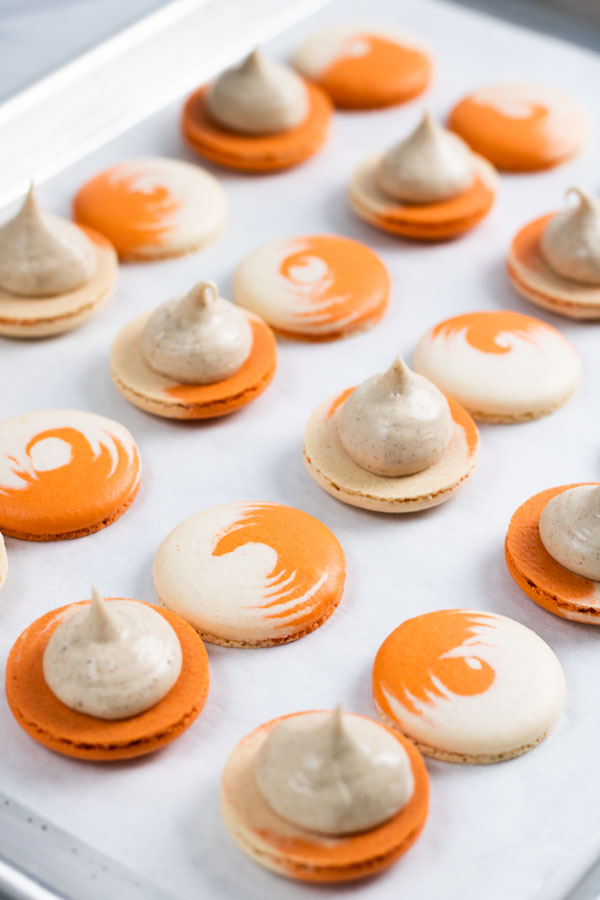 orange and white swirled pumpkin cheesecake macarons shells with pumpkin cheesecake filling