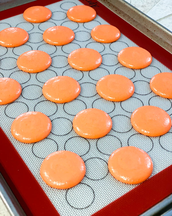 Orange pumpkin spice macarons on baking mat