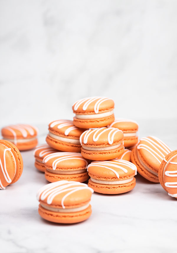 Orange pumpkin spice macarons with white drizzle