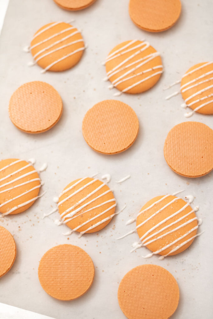 orange salted caramel macaron shells on parchment paper