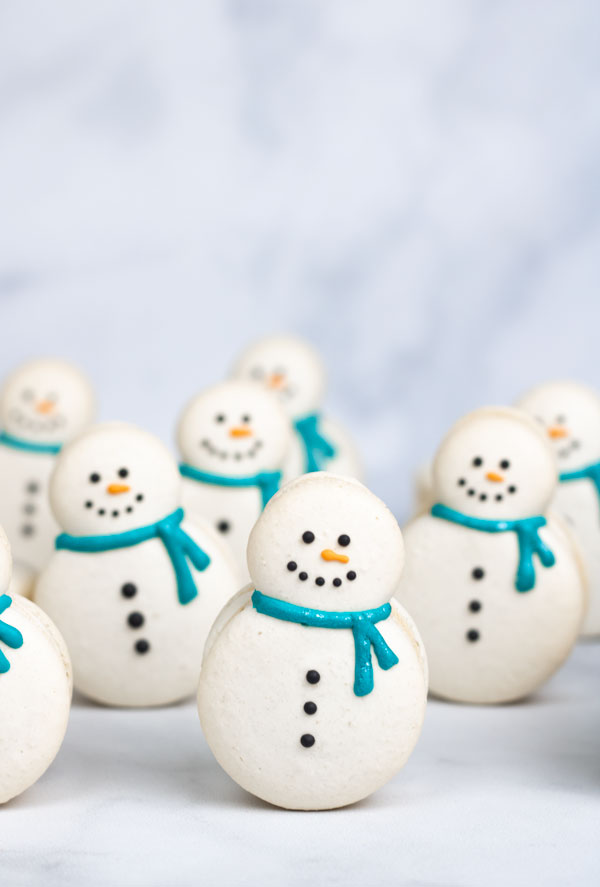 decorated snowman macarons in front of other macarons
