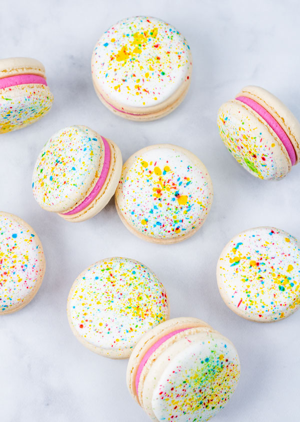 splatter paint macarons with pink buttercream on white background