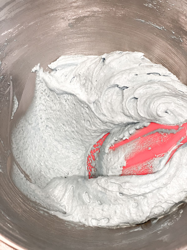 light blue macaron batter and red spatula in mixing bowl