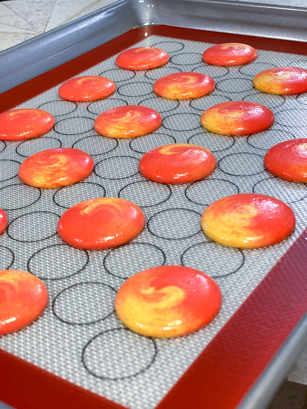 red and yellow unbaked macarons on silicone mat