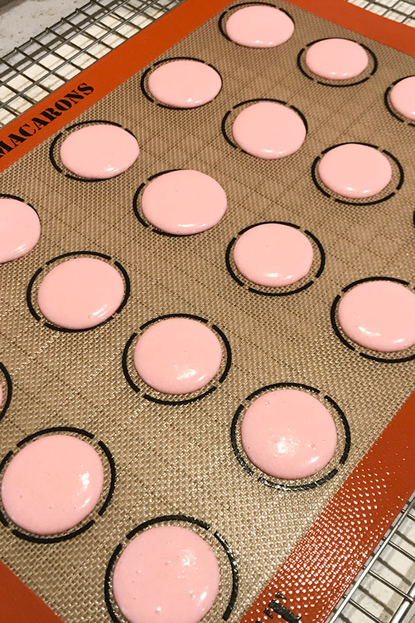 pink unbaked macarons on silicone mat