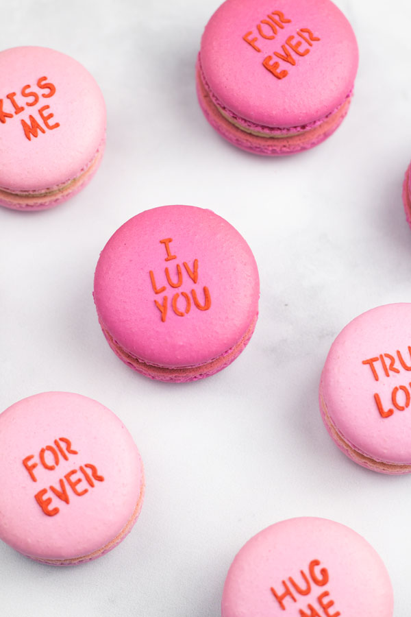Light pink and dark pink conversation heart macarons on white background